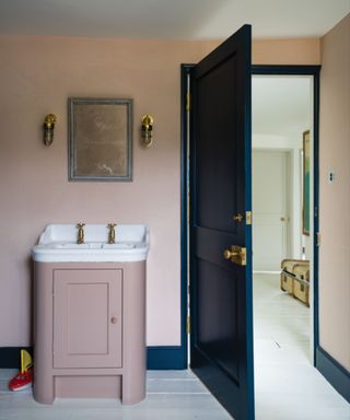 bathroom with plaster pink walls and sink vanity unit, dark blue-green door and woodwork