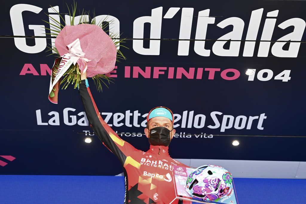 VALLE SPLUGA ALPE MOTTA ITALY MAY 29 Damiano Caruso of Italy and Team Bahrain Victorious celebrates at podium during the 104th Giro dItalia 2021 Stage 20 a 164km stage from Verbania to Valle Spluga Alpe Motta 1727m Kask Utopia Giro Helmet designed by MotoGP artist Aldo Drudi to stage winners The peloton passing through flowery landscape UCIworldtour girodiitalia Giro on May 29 2021 in Valle Spluga Alpe Motta Italy Photo by Stuart FranklinGetty Images