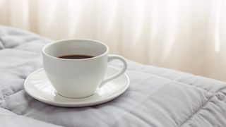 A white cup containing coffee placed on a white mattress