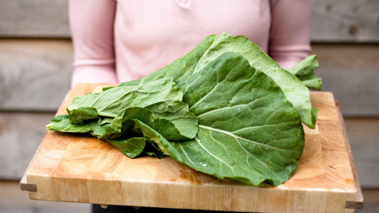 Organic collard green leaves on a wooden board