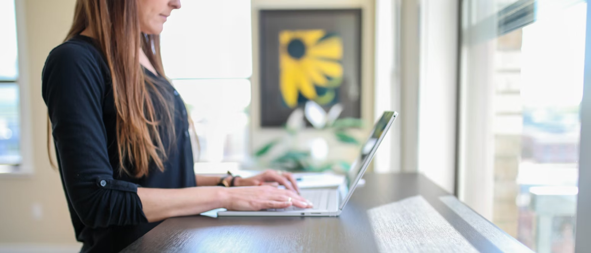 Woman using a laptop on a standing desk in an office