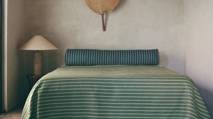 A striped bed spread with bolster cushion
