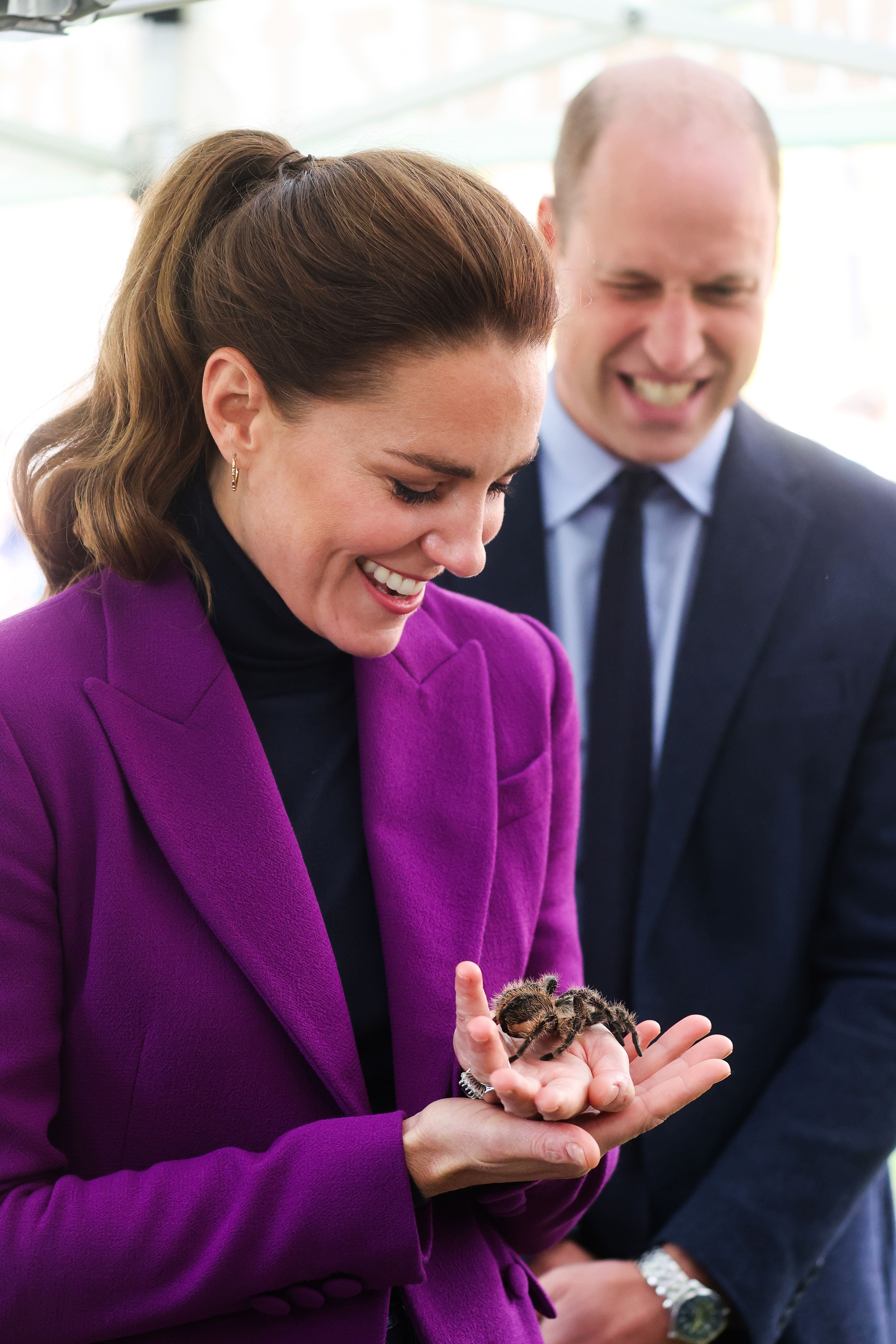 Kate Middleton holding a spider as Prince William looks on