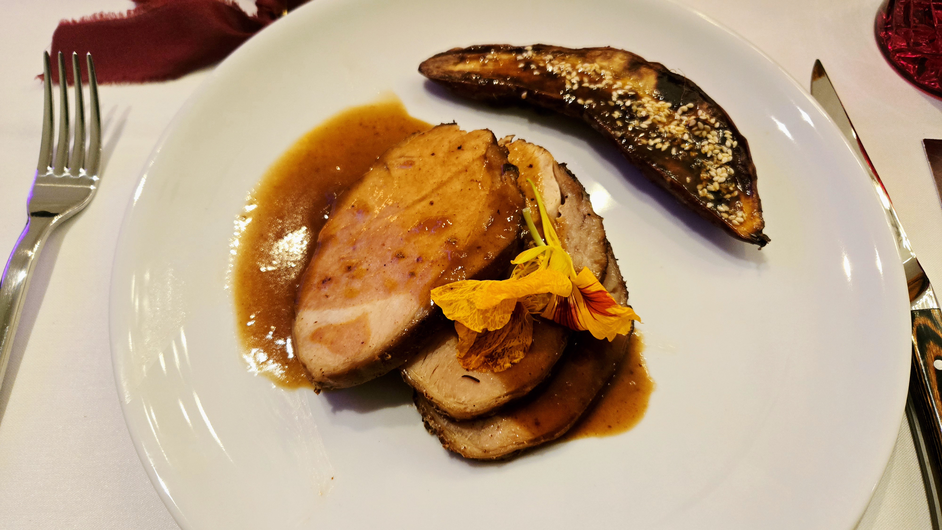 A plate of sliced roasted turkey breast with gravy and a side of Japanese sweet potatoes
