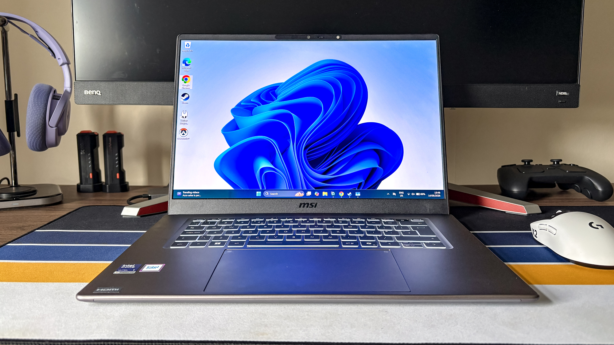 MSI Prestige 16 AI+ on desk with mouse, controller and headphones in background