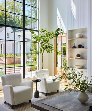 double height steel framed windows in family living room with white walls