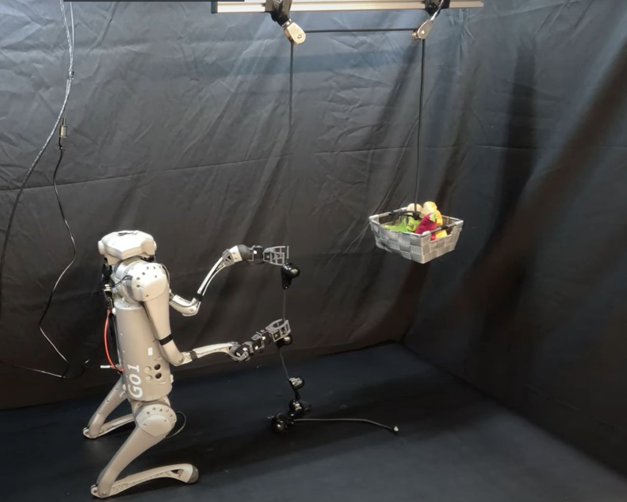 Robot pulling string to lift basket of fruit.
