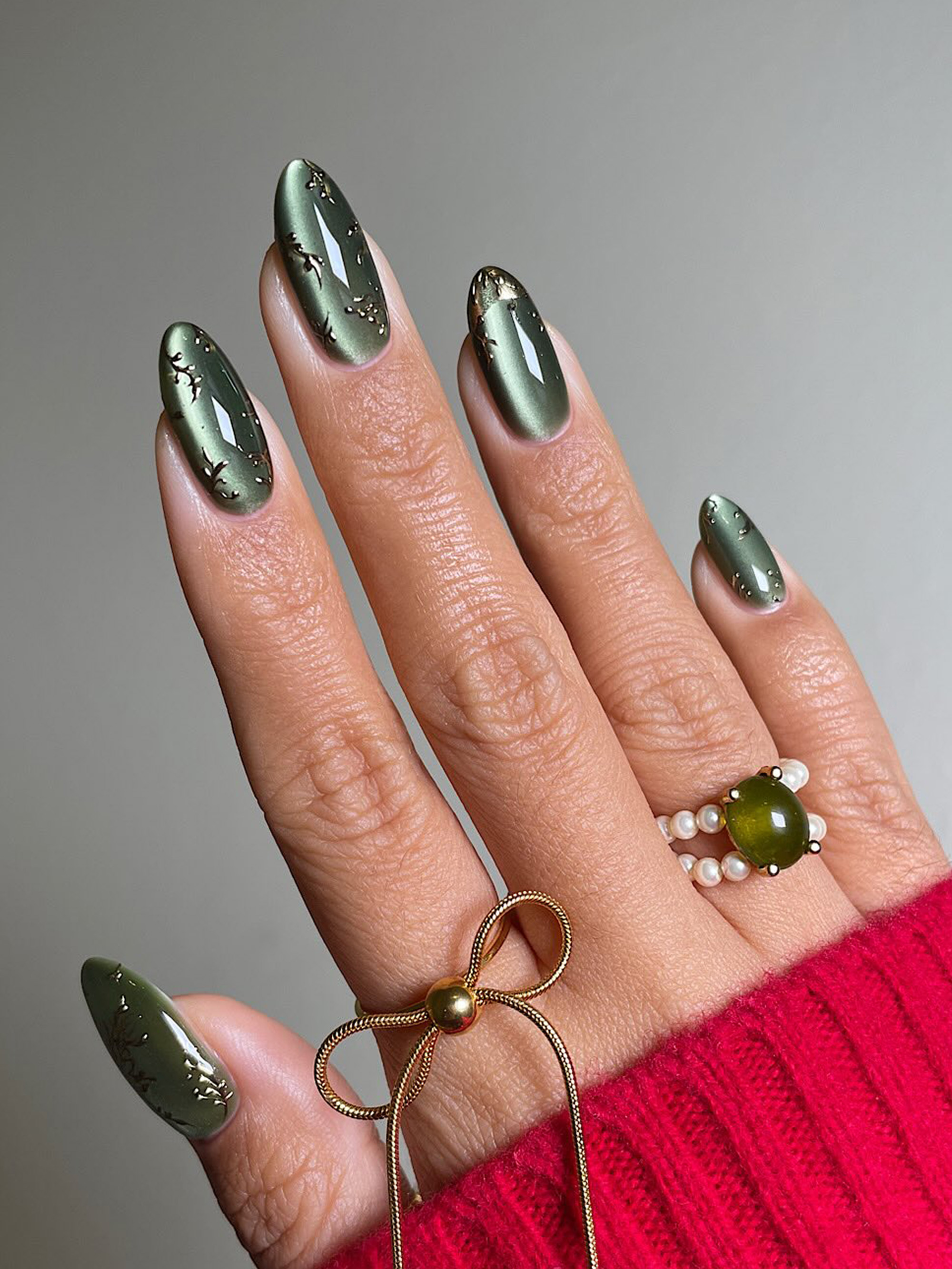 A green cat eye manicure with gold details by San Sung Kim