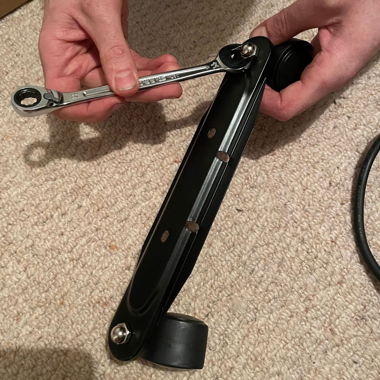 Using a spanner to screw castor wheels onto the legs of an oil-filled radiator