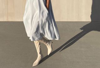 A woman wears a pale-blue silk midi dress with white knee-high sock booties.