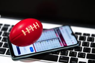 red toy football on top of phone balanced on computer keyboard