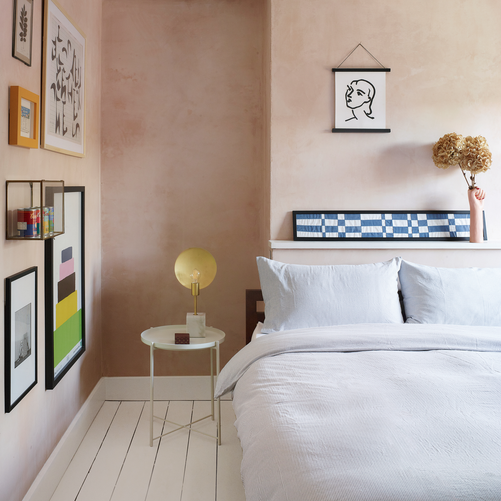 A plaster pink bedroom with a gallery wall