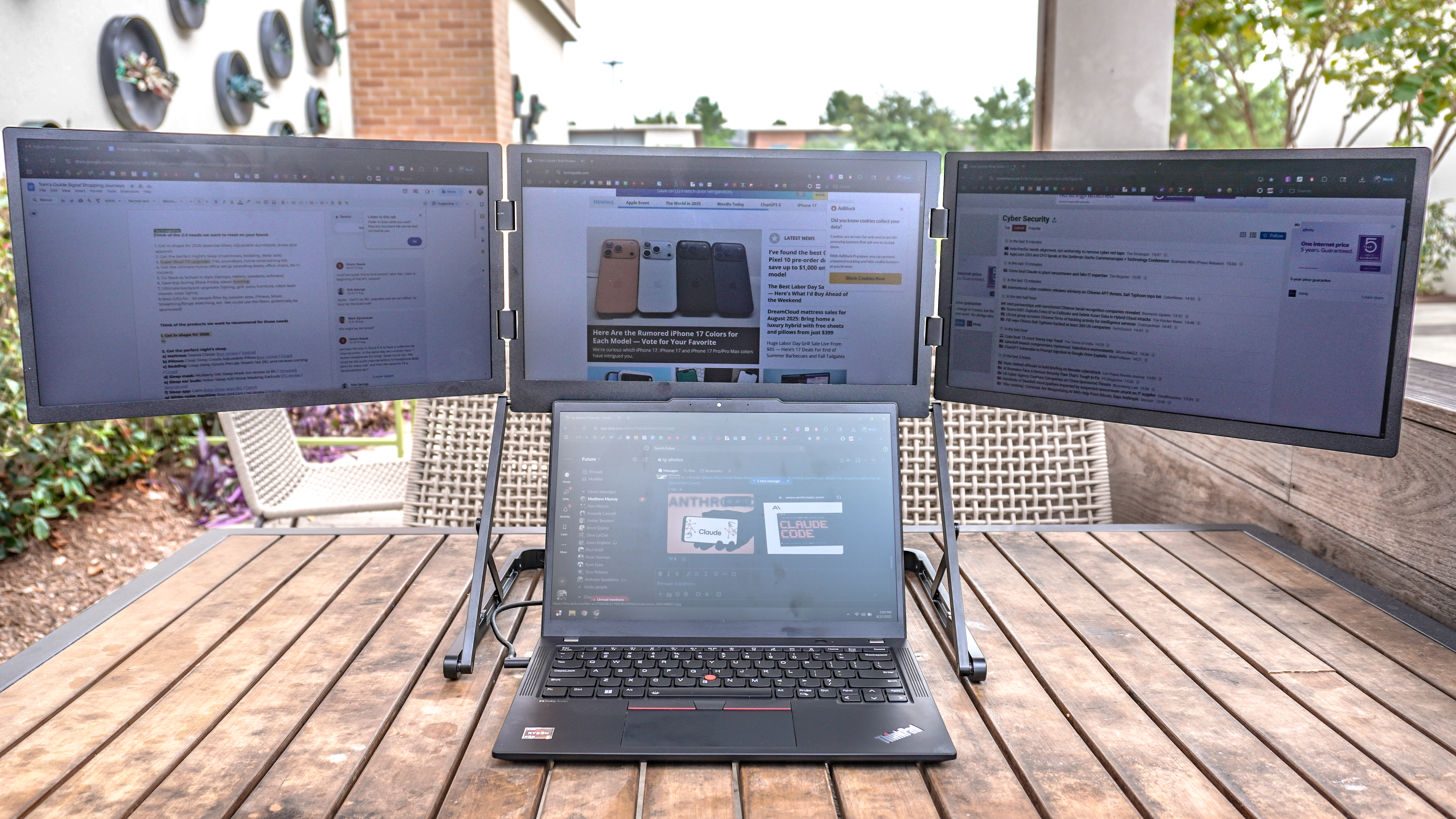 The Aura Triple Aero 15.6 Pro Max portable monitor connected to a ThinkPad laptop with multiple websites open on each of its three displays