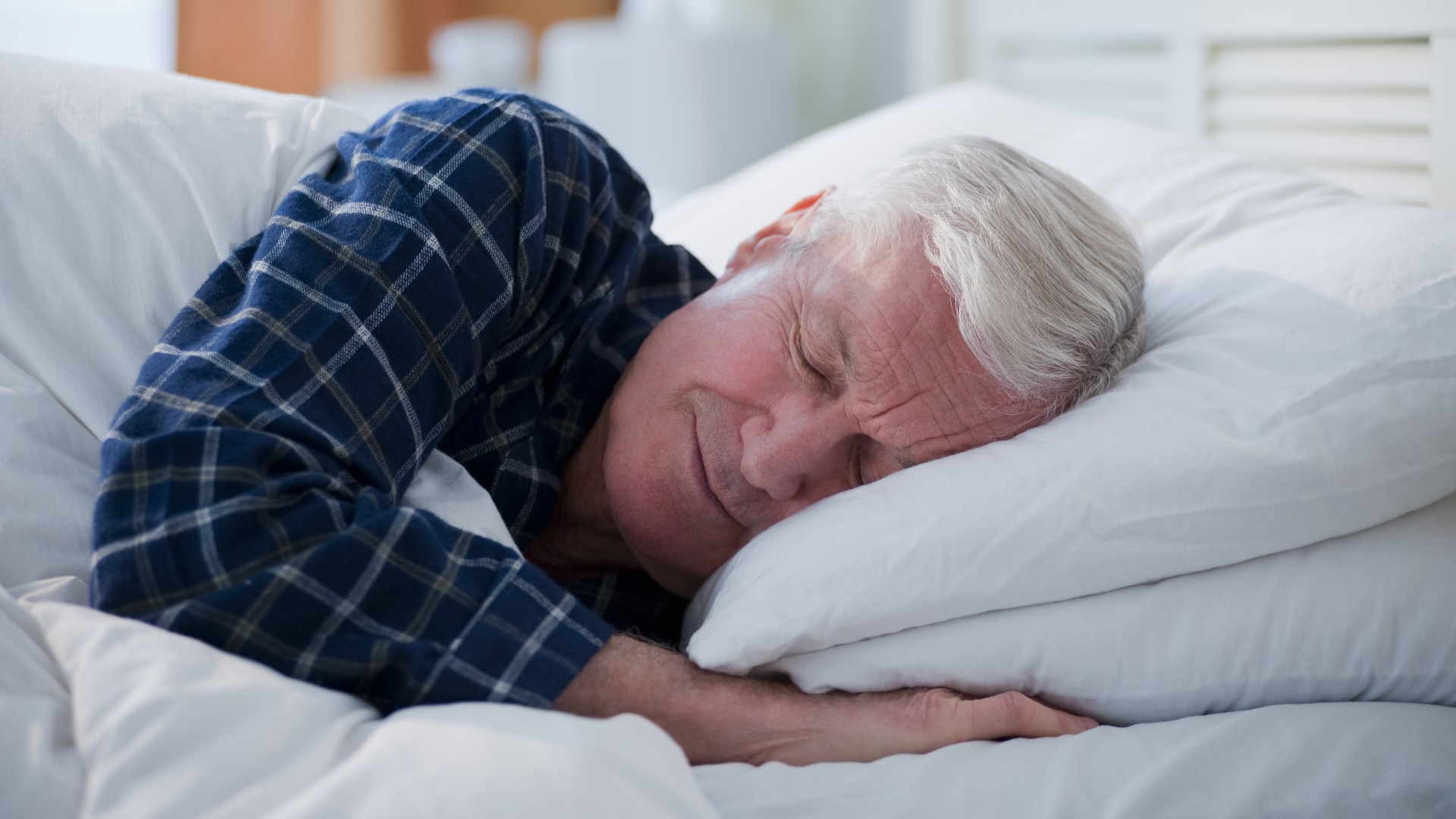 An elderly man sleeps in bed