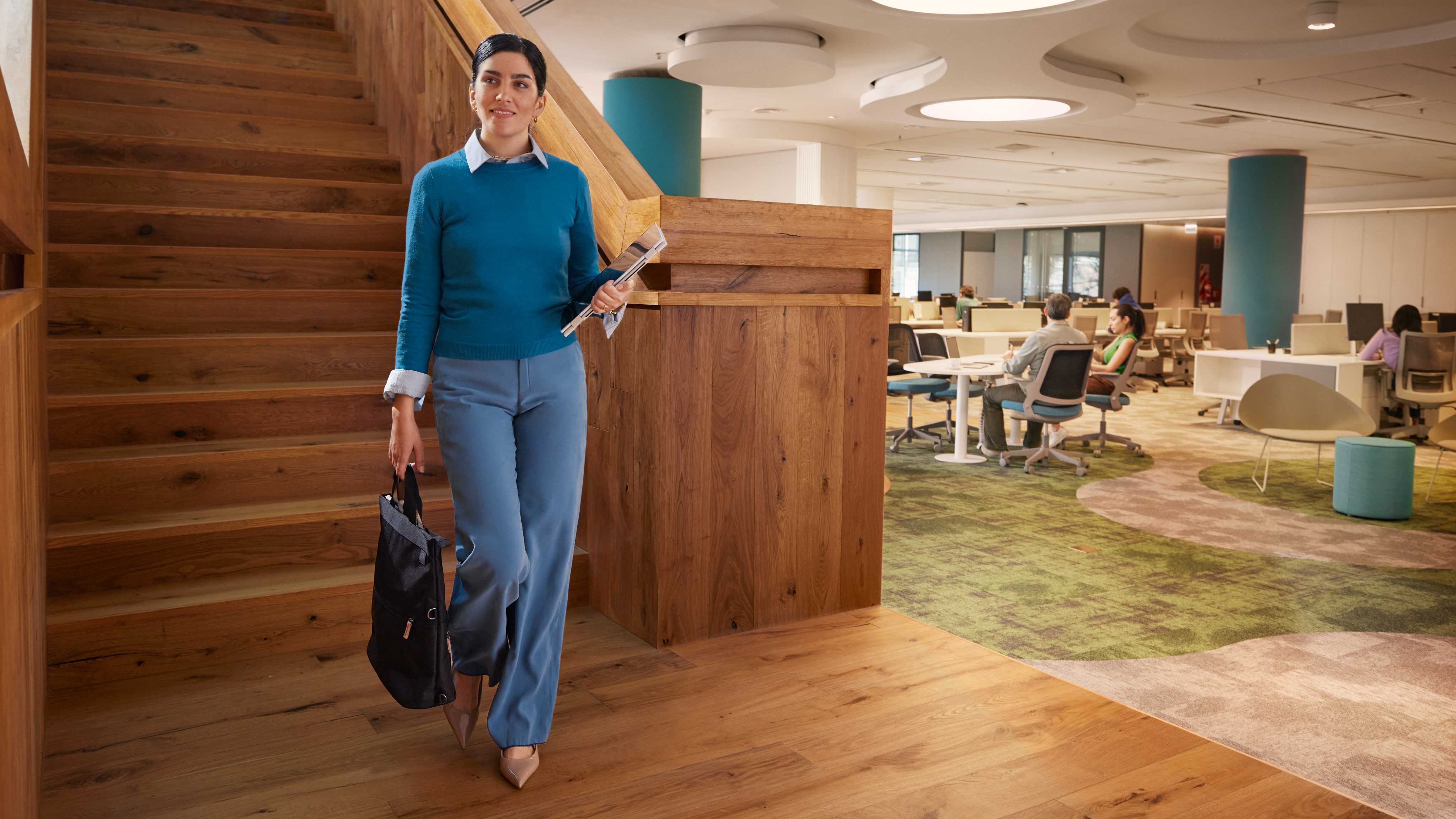 A person walking down stairs while holding the HP EliteBook X Flip 14 (G1i) in tablet mode.