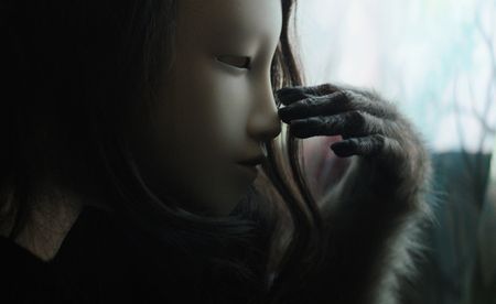 Pierre Huyghe artwork, Untitled (Human Mask), girl's face with ape-like arm touching face, from the Venice exhibition ‘Liminal’