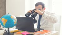 Person using binoculars to search on their laptop for Black Friday deals