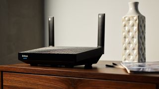 Lifestyle shot of the Linksys Hydra Pro 6 Wi-Fi router atop a side table in a well-appointed living room.