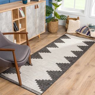 A black and white aztec runner rugs sits on a light wooden floor