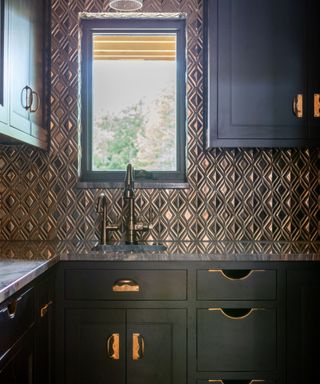 kitchen with black cabinets, metallic textured walls and brass hardware