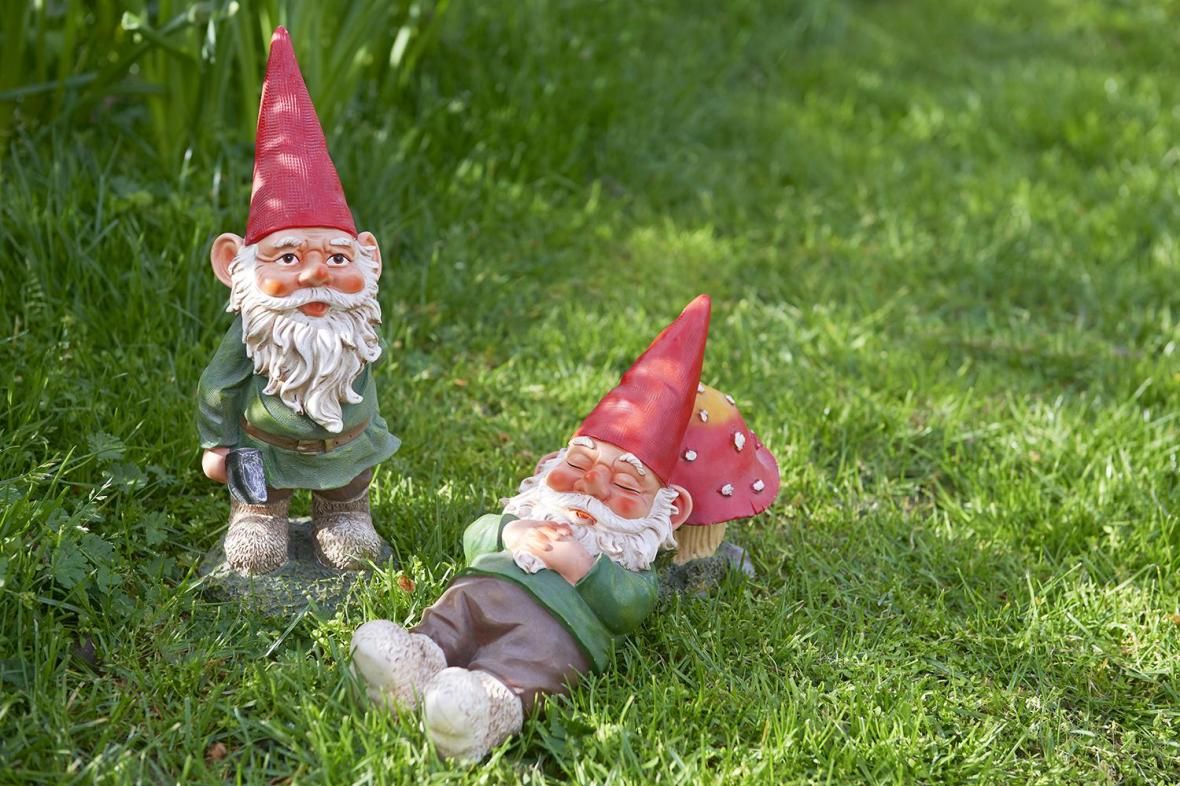 Two garden gnomes relaxing in their garden.