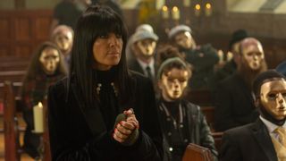 Claudia Winkleman stood in front of masked contestants in The Traitors