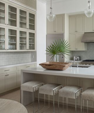 Pale green kitchen with aloe green units, bar stools, kitchen island, glazed wall units