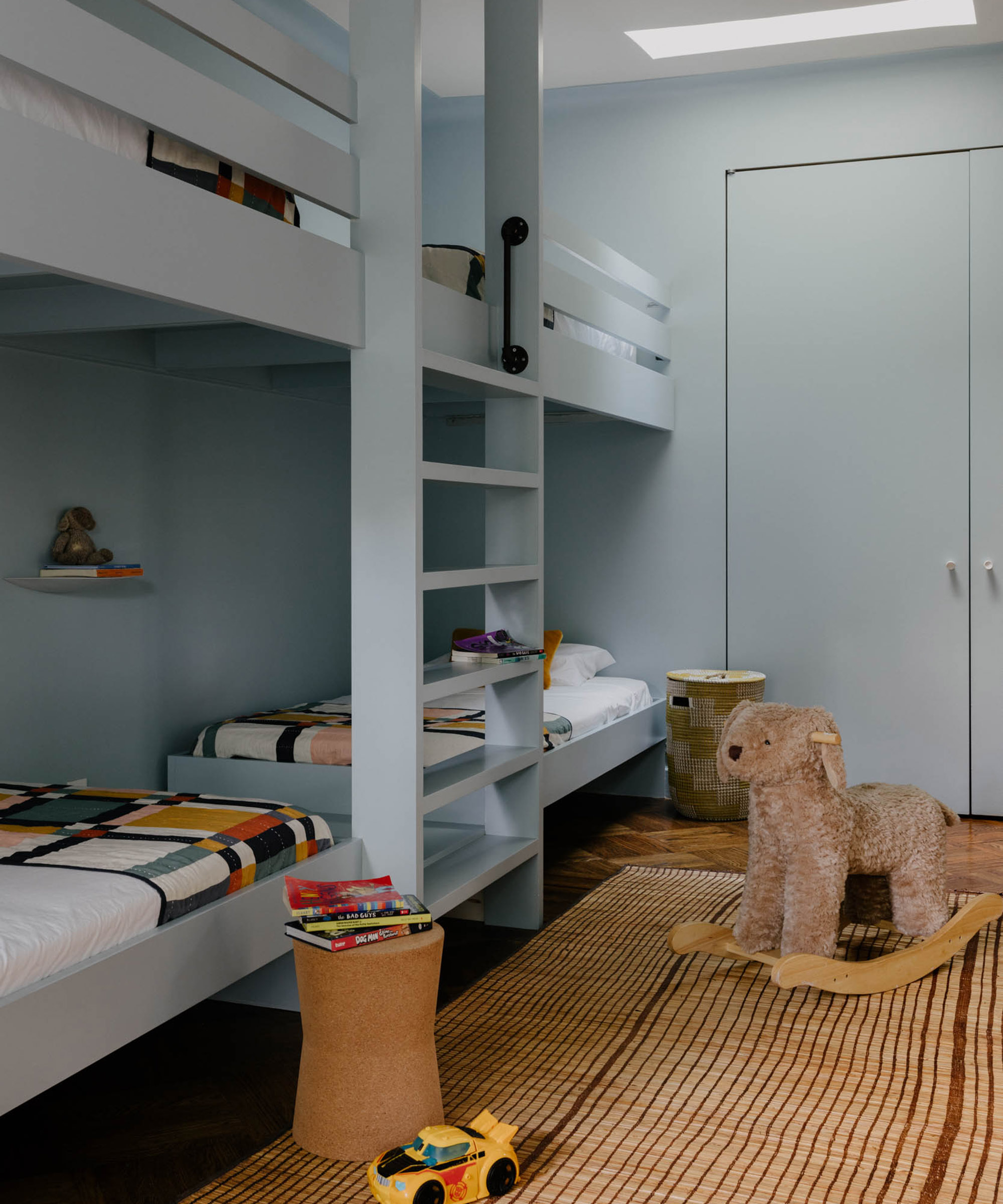 kid's bunk room with pale blue joinery and sisal rug with rocking horse on it