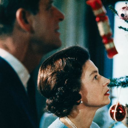 Queen Elizabeth and Prince Philip looking up at a Christmas tree decorated with red and white ornaments