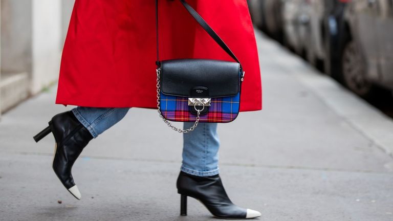 A woman in a red coat walking holding a Mulberry bag to represent the start of Mulberry Black Friday deals