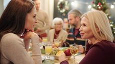 A young woman and an older woman have a chat at the holiday dinner table.