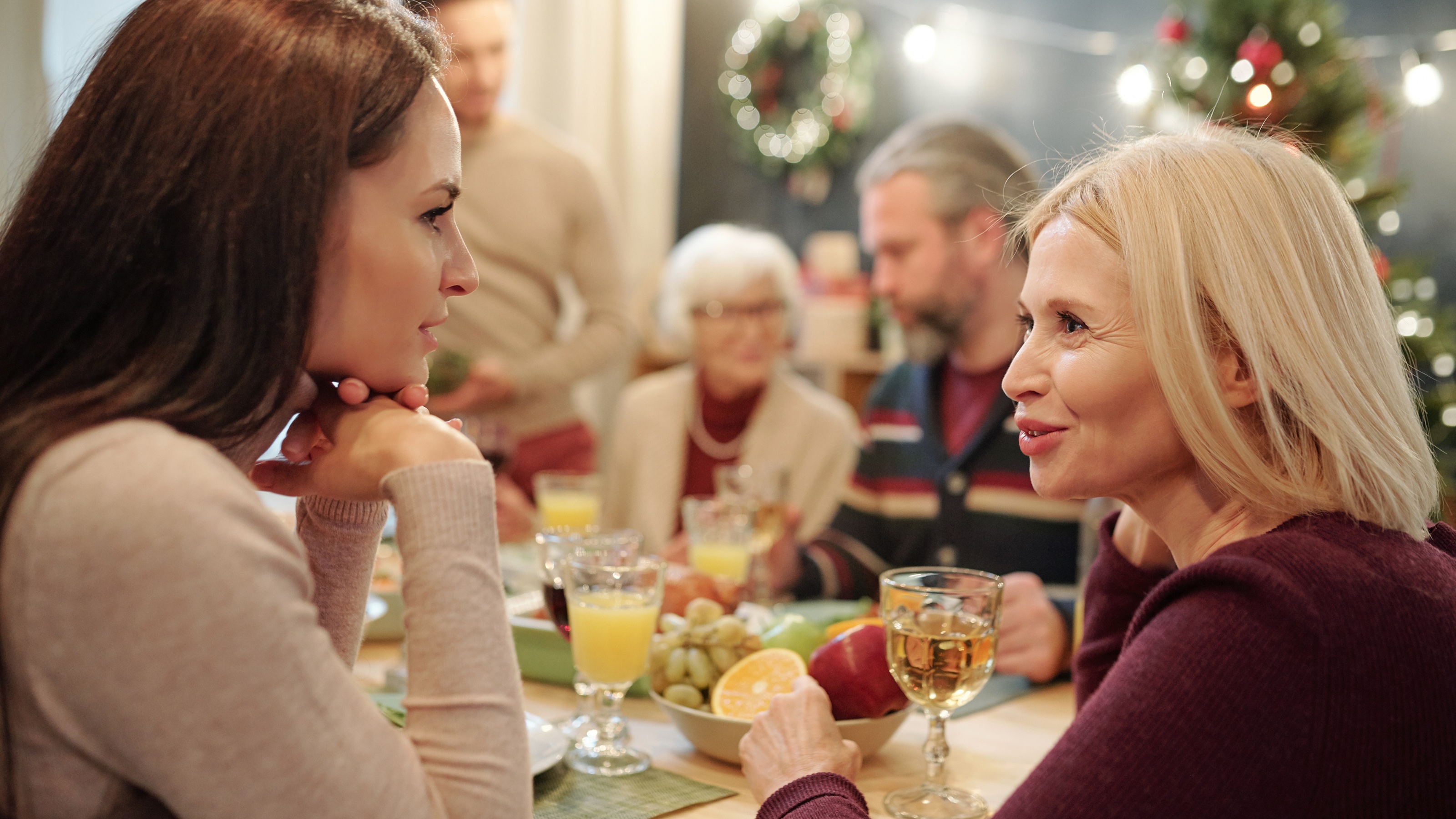 A young woman and an older woman have a chat at the holiday dinner table.