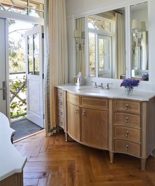 traditional bathroom with oak vanity unit and original wooden floorboards in a herringbone pattern