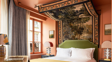 A pink bedroom with a fabric four poster headboard, designed by Martin Brudnizki