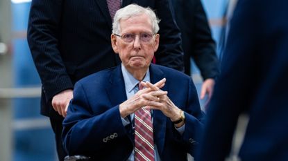 Senator Mitch McConnell is pushed in a wheelchair 