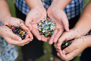 Kids' hands holding piles of glitter