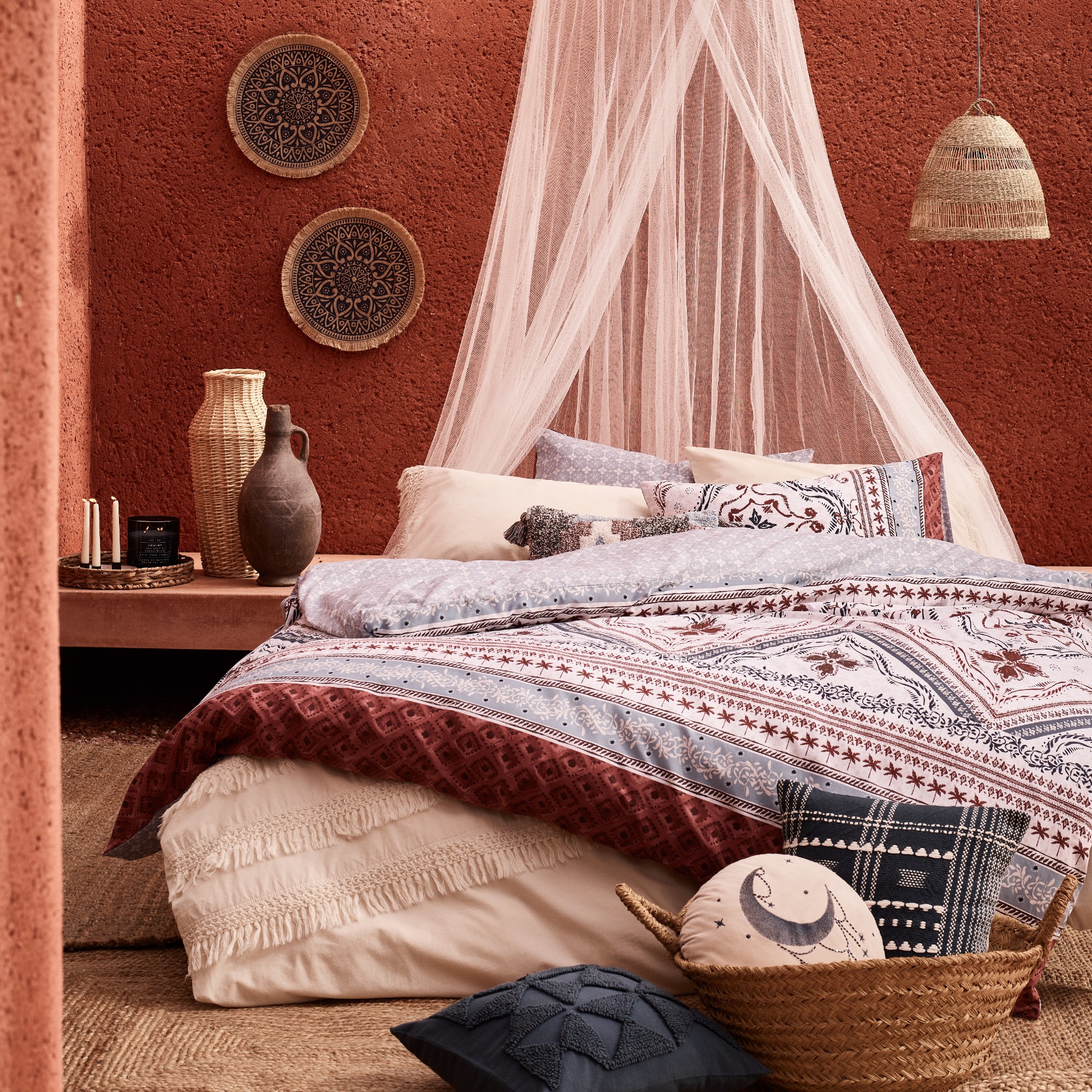 A terracotta-painted bedroom with a bed and a sheer white canopy