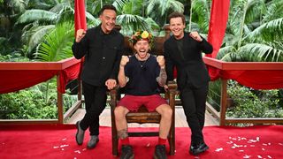 Danny Jones sitting in his jungle throne with his King of the jungle crown on and Ant and Dec standing either side of him.