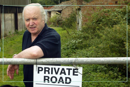 Tony Martin leaning on a fence with a 'Privat Road' sign attached to it