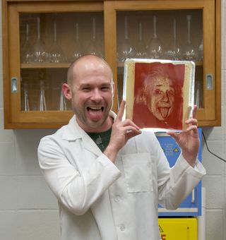 Zachary Copfer poses with his version of a famous photo of Albert Einstein. When displaying his portraits, he plays with the relationship between art and science by labeling Einstein and Darwin as his favorite artists, and artists Pablo Picasso and Leonar