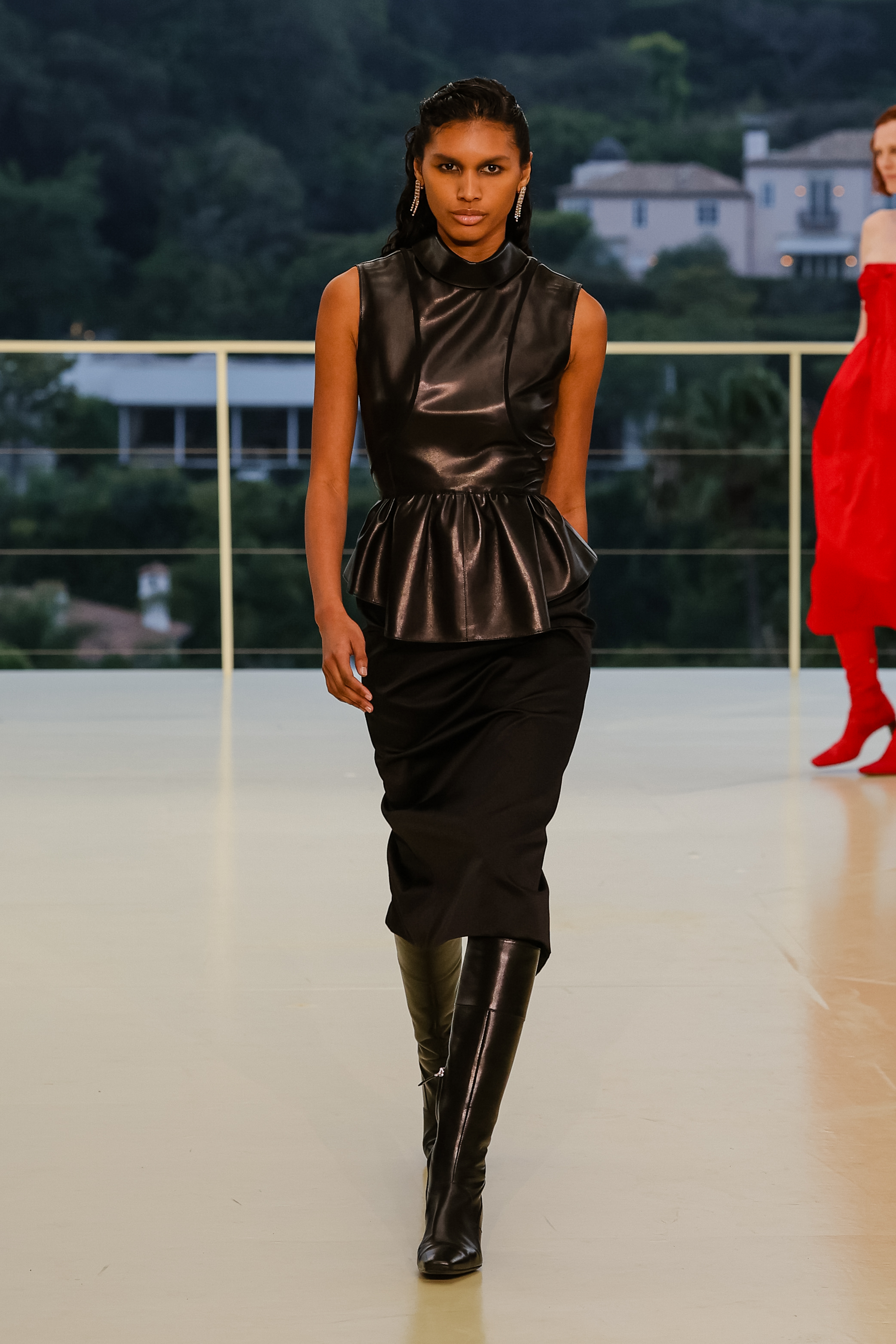 a woman wears a black leather top and pants with boots.
