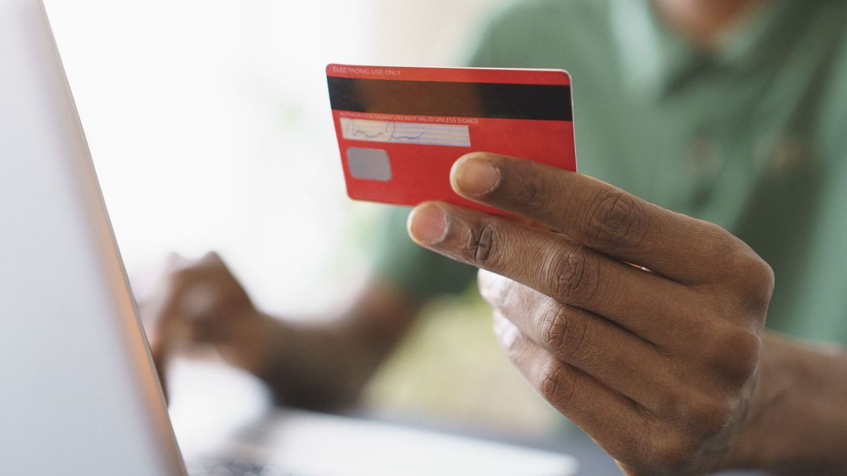 Cropped image of man holding a credit card while shopping online