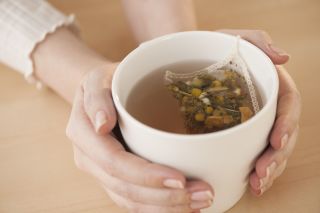 A close up of a woman holding a mug of chamomile tea