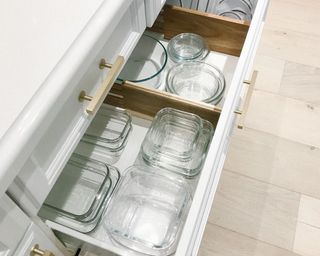 A white kitchen drawer with glass food storage containers and Acacia wood spring loaded dividers