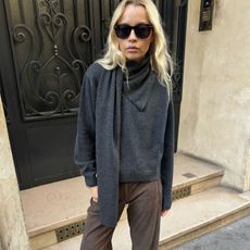 A woman wearing a gray sweater and brown pants