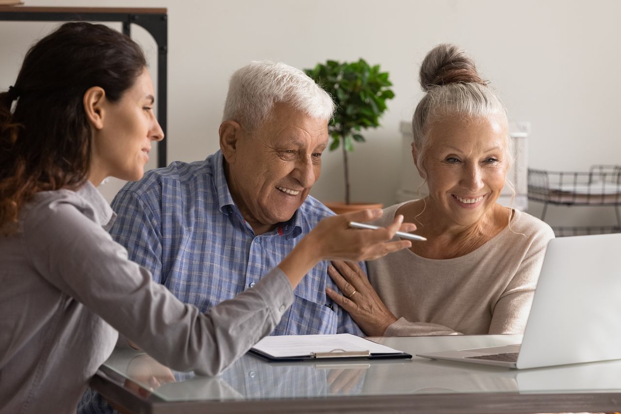 An older couple sits with a professional helping with their finances. 