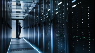 A man standing in front of a rack of servers inside a data center.