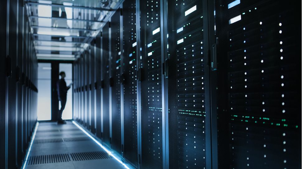 A man standing in front of a rack of servers inside a data center