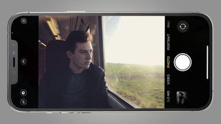 A man looking out of a train window on a phone screen