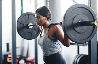 How much weight should you start lifting?: Cropped shot of a young woman working out with a barbell at the gym